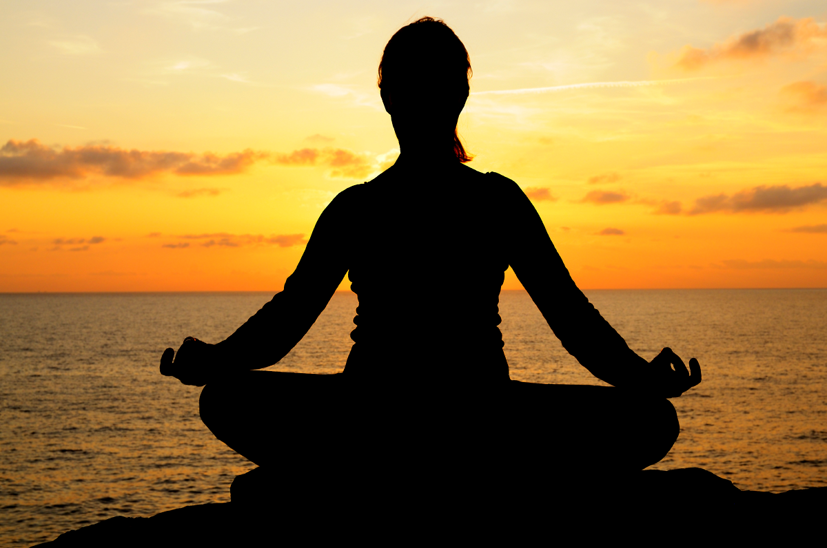 A Woman Meditating Facing The Sunset